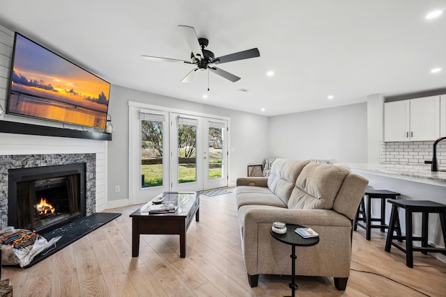 living room featuring a ceiling fan, recessed lighting, a high end fireplace, and light wood-style floors