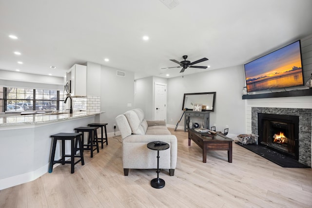 living area featuring light wood finished floors, a fireplace, visible vents, and recessed lighting