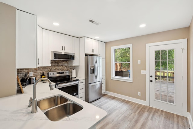 1166 Julian Clark Rd, Charleston, SC 29412 - kitchen with appliances with stainless steel finishes, a sink, light stone counters, tasteful backsplash, and white cabinets