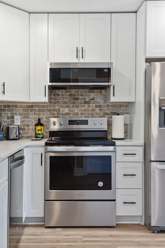 1166 Julian Clark Rd, Charleston, SC 29412 - kitchen with appliances with stainless steel finishes, light countertops, white cabinets, light wood-type flooring, and backsplash