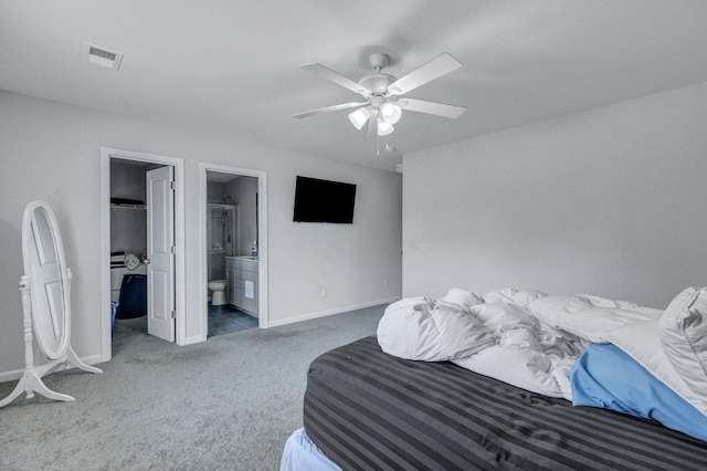 carpeted bedroom with a spacious closet, visible vents, ceiling fan, baseboards, and ensuite bathroom