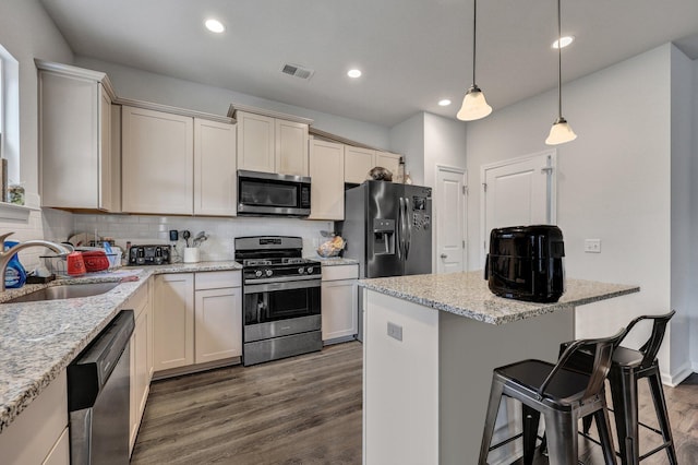 kitchen with visible vents, a sink, decorative backsplash, dark wood-type flooring, and appliances with stainless steel finishes