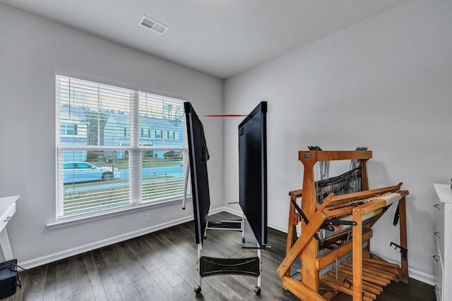 workout area with visible vents, baseboards, and wood finished floors