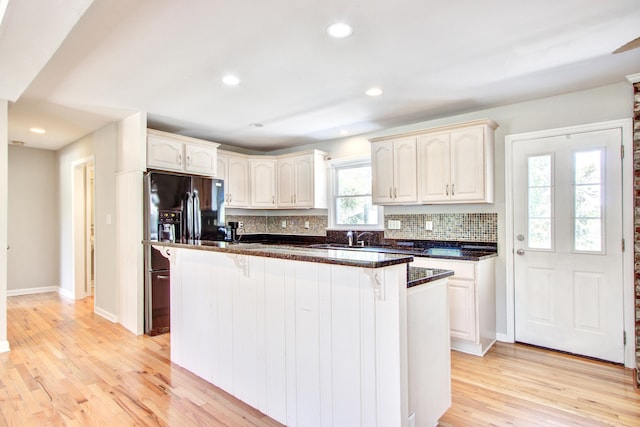 1834 Cornish Ave, Charleston, SC 29412 - kitchen featuring decorative backsplash, baseboards, a breakfast bar area, light wood finished floors, and black fridge