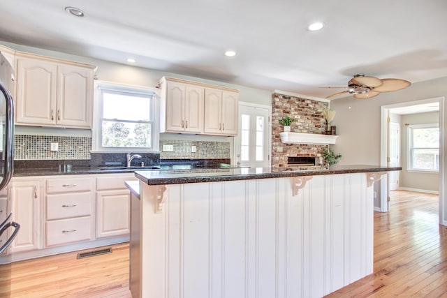 1834 Cornish Ave, Charleston, SC 29412 - kitchen with ceiling fan, a kitchen bar, tasteful backsplash, a sink, and light wood finished floors