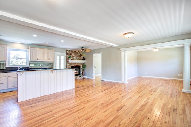 1834 Cornish Ave, Charleston, SC 29412 - kitchen featuring decorative columns, dark countertops, open floor plan, a large fireplace, and light wood-style flooring
