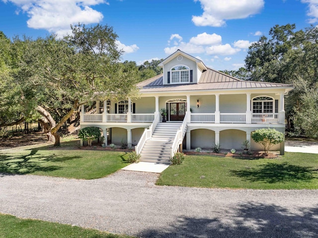 view of front of house with a porch, a front yard, gravel driveway, and stairway