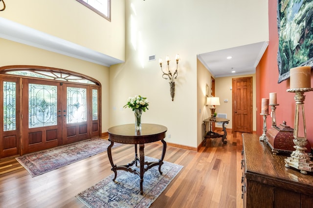 entryway with ornamental molding, light wood-type flooring, visible vents, and baseboards