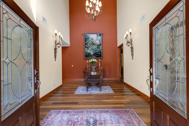 foyer featuring a chandelier, a high ceiling, dark wood finished floors, and visible vents