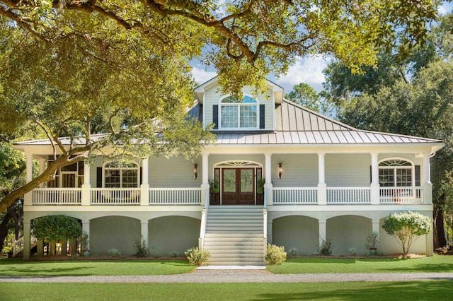 view of front facade featuring a standing seam roof, a front yard, metal roof, and french doors