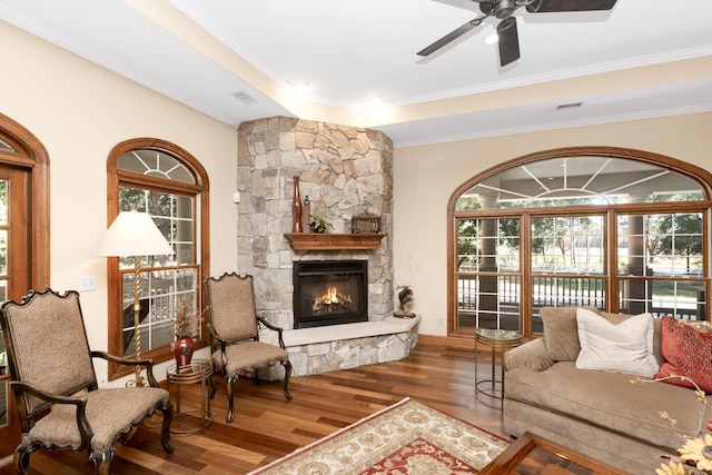 living area featuring visible vents, a ceiling fan, dark wood-style flooring, crown molding, and a fireplace