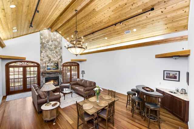 living area featuring french doors, a fireplace, wood ceiling, and a healthy amount of sunlight