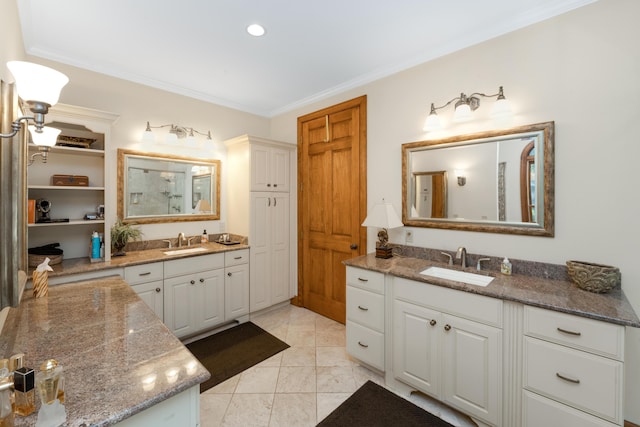 bathroom with ornamental molding, a closet, two vanities, and a sink