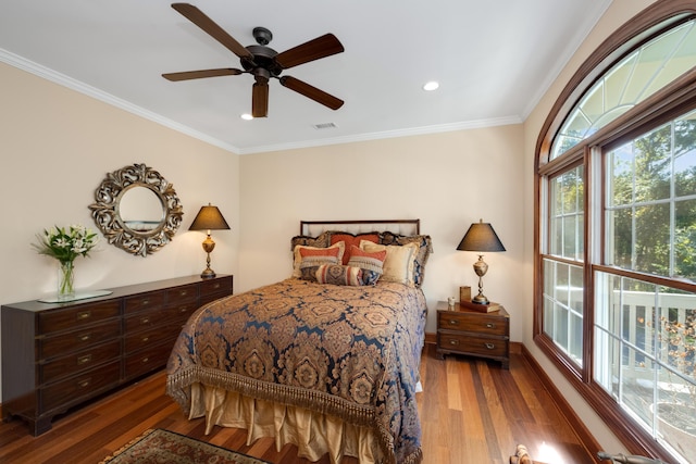 bedroom featuring ceiling fan, ornamental molding, wood finished floors, and visible vents