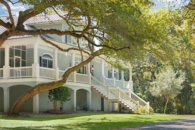 view of side of property featuring a standing seam roof, metal roof, stairway, and a lawn