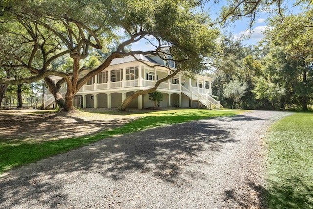 view of front facade featuring driveway, a front lawn, and stairs