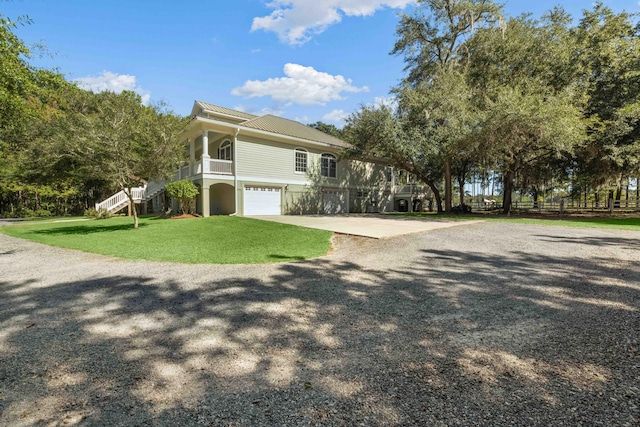 view of front facade featuring metal roof, an attached garage, driveway, stairway, and a front lawn