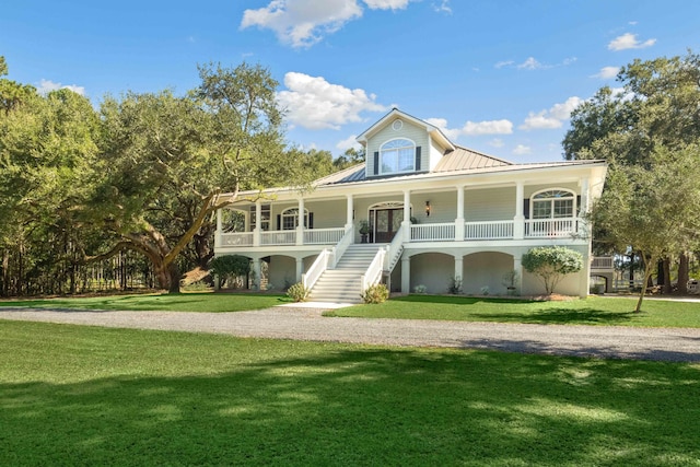 view of front of property featuring metal roof, a porch, stairway, a standing seam roof, and a front yard