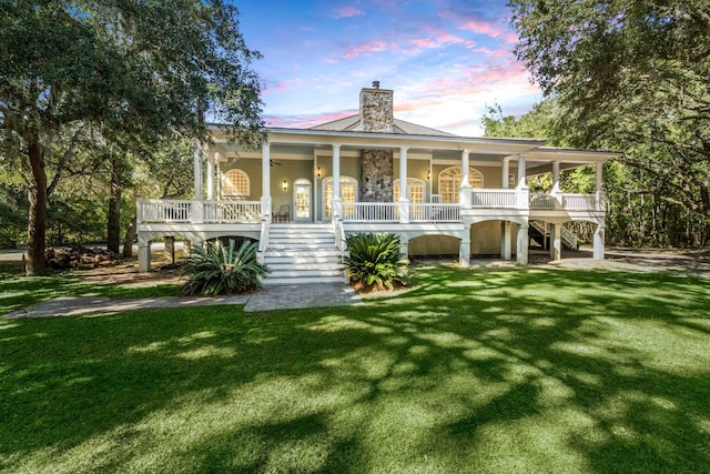 rear view of house with stairs, a porch, and a lawn