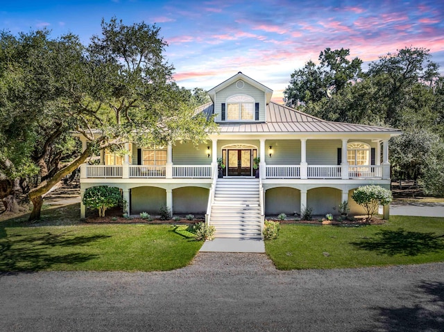 view of front of property featuring gravel driveway, a standing seam roof, french doors, and a yard