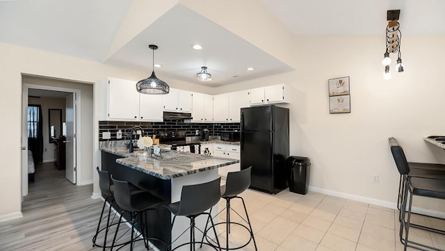 2172 Palermo Pl, North Charleston, SC 29406 - kitchen with black appliances, under cabinet range hood, dark stone countertops, decorative backsplash, and white cabinets