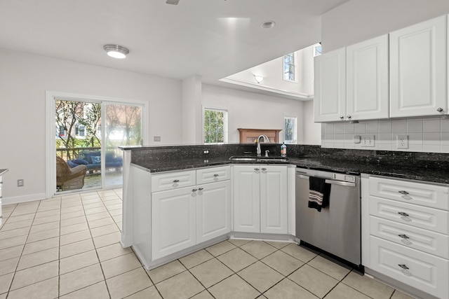 kitchen featuring light tile patterned floors, decorative backsplash, a peninsula, stainless steel dishwasher, and a sink