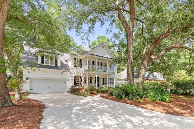 neoclassical home with a shingled roof, covered porch, a balcony, a garage, and driveway