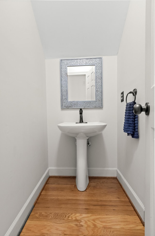 bathroom featuring lofted ceiling, baseboards, and wood finished floors