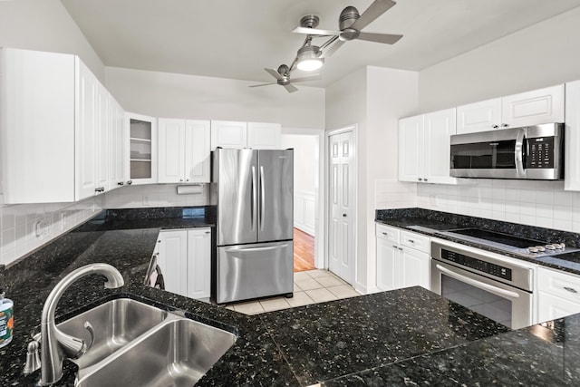 kitchen with a ceiling fan, a sink, appliances with stainless steel finishes, white cabinets, and decorative backsplash