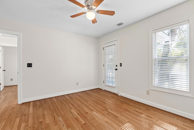 empty room with baseboards, light wood-style floors, visible vents, and ceiling fan