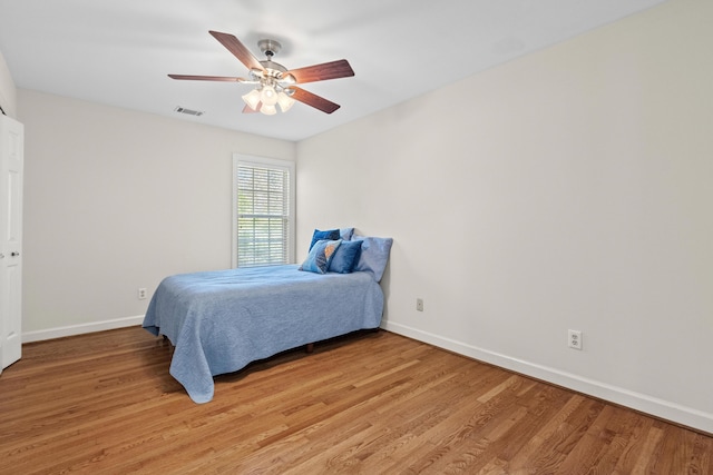 bedroom featuring baseboards, visible vents, light wood finished floors, and ceiling fan