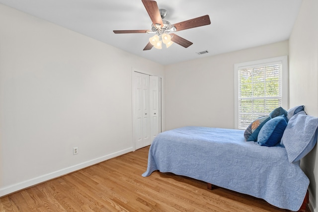 bedroom featuring light wood-type flooring, visible vents, baseboards, and a ceiling fan