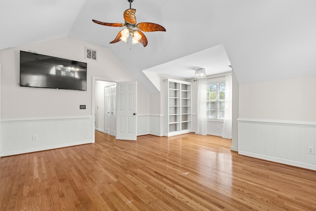 unfurnished living room featuring wainscoting, light wood-type flooring, and ceiling fan