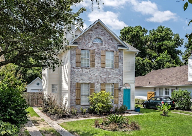 traditional-style home featuring a front lawn, fence, and brick siding