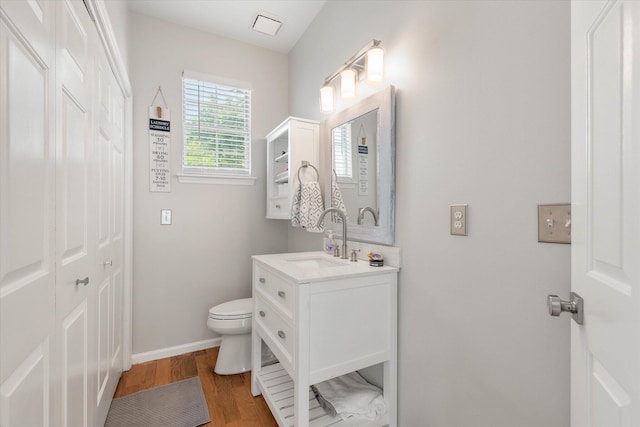 bathroom with vanity, wood finished floors, toilet, and baseboards