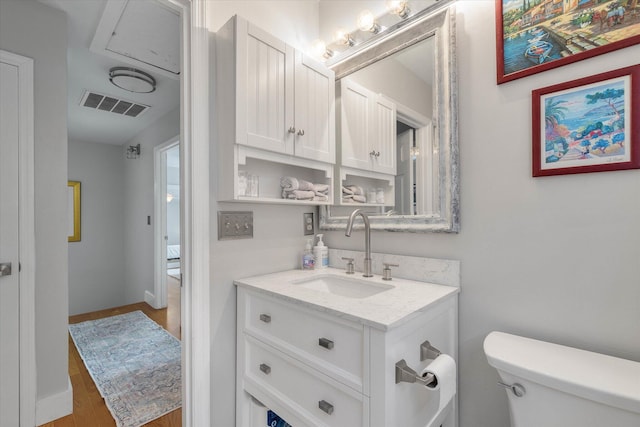 half bathroom featuring toilet, vanity, visible vents, and baseboards