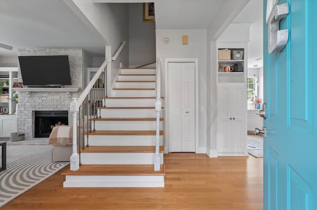 foyer with stairs, a fireplace, and wood finished floors