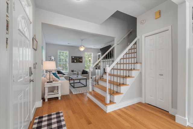 stairway featuring baseboards, a ceiling fan, and wood finished floors