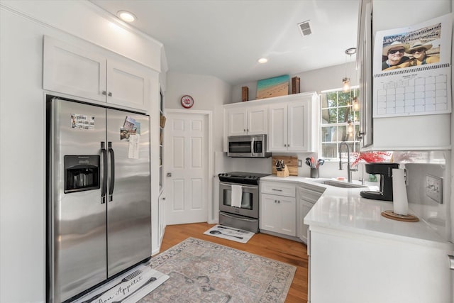 kitchen featuring appliances with stainless steel finishes, light hardwood / wood-style flooring, backsplash, sink, and white cabinets