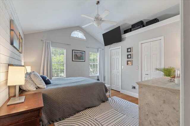 bedroom with ceiling fan, lofted ceiling, hardwood / wood-style floors, and multiple closets