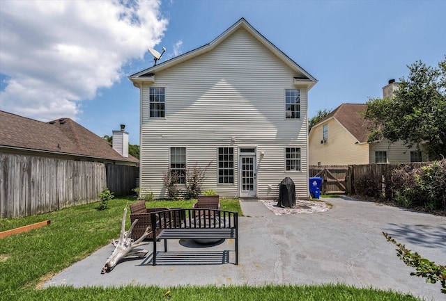 rear view of house featuring a fenced backyard, a gate, a lawn, and a patio