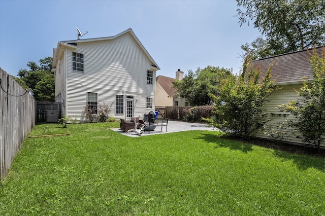 rear view of house featuring a fenced backyard, a patio, and a lawn