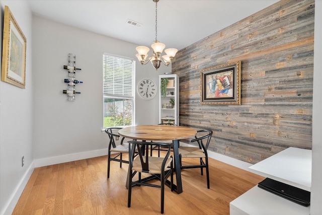 dining space featuring visible vents, baseboards, light wood-style flooring, an accent wall, and a chandelier