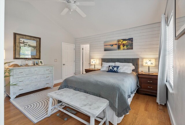 bedroom featuring light wood-style floors, vaulted ceiling, baseboards, and a ceiling fan