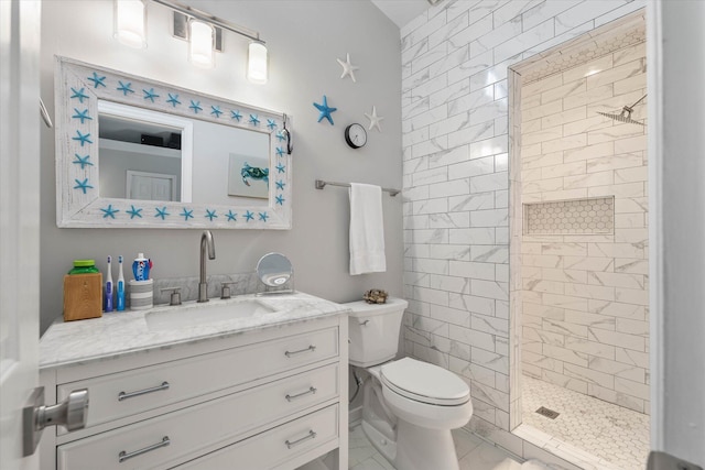 bathroom with tile patterned floors, vanity, tiled shower, and toilet