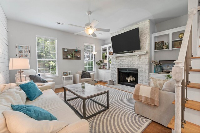 living room with ceiling fan, a fireplace, and light hardwood / wood-style floors