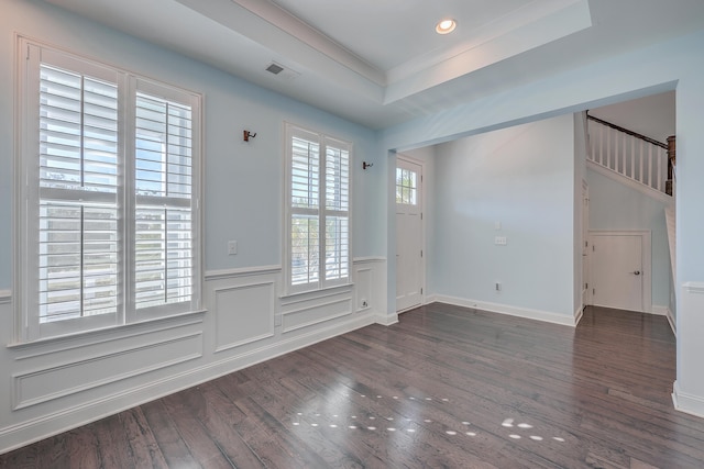 spare room with ornamental molding, a tray ceiling, and dark hardwood / wood-style flooring