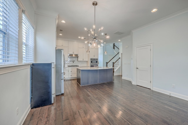 kitchen featuring white cabinets, dark hardwood / wood-style flooring, a kitchen island, decorative light fixtures, and stainless steel appliances