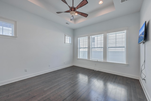 unfurnished room featuring dark wood-type flooring, ceiling fan, and a tray ceiling