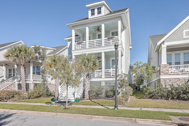 beach home featuring covered porch, a front lawn, and ceiling fan